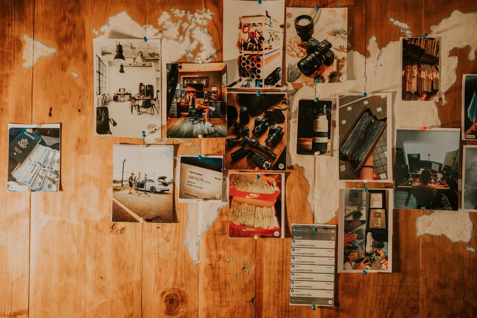 Artistic arrangement of various photographs pinned on a wooden wall, showcasing creativity.