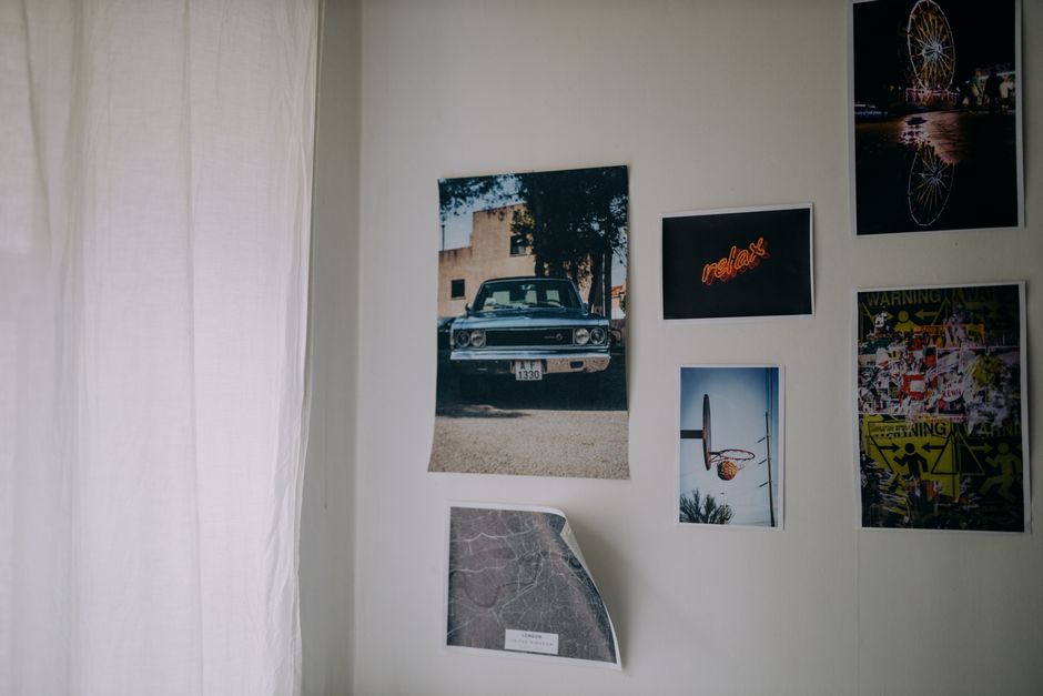 A collection of posters and photographs on a white wall, creating an artistic ambiance.